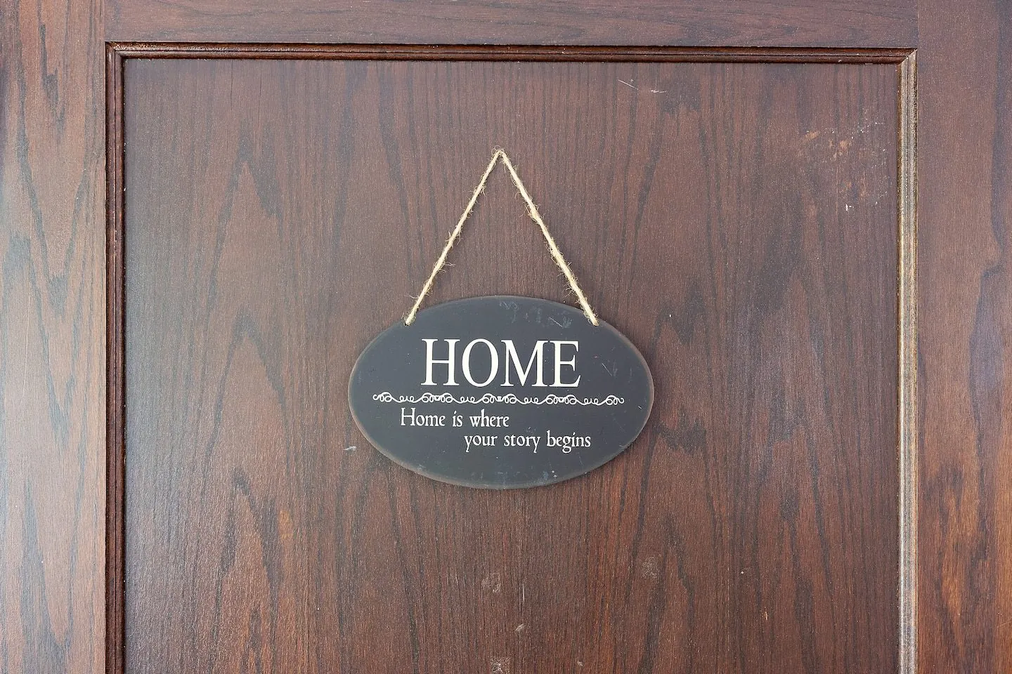 A wooden 'Home' sign on the oak door